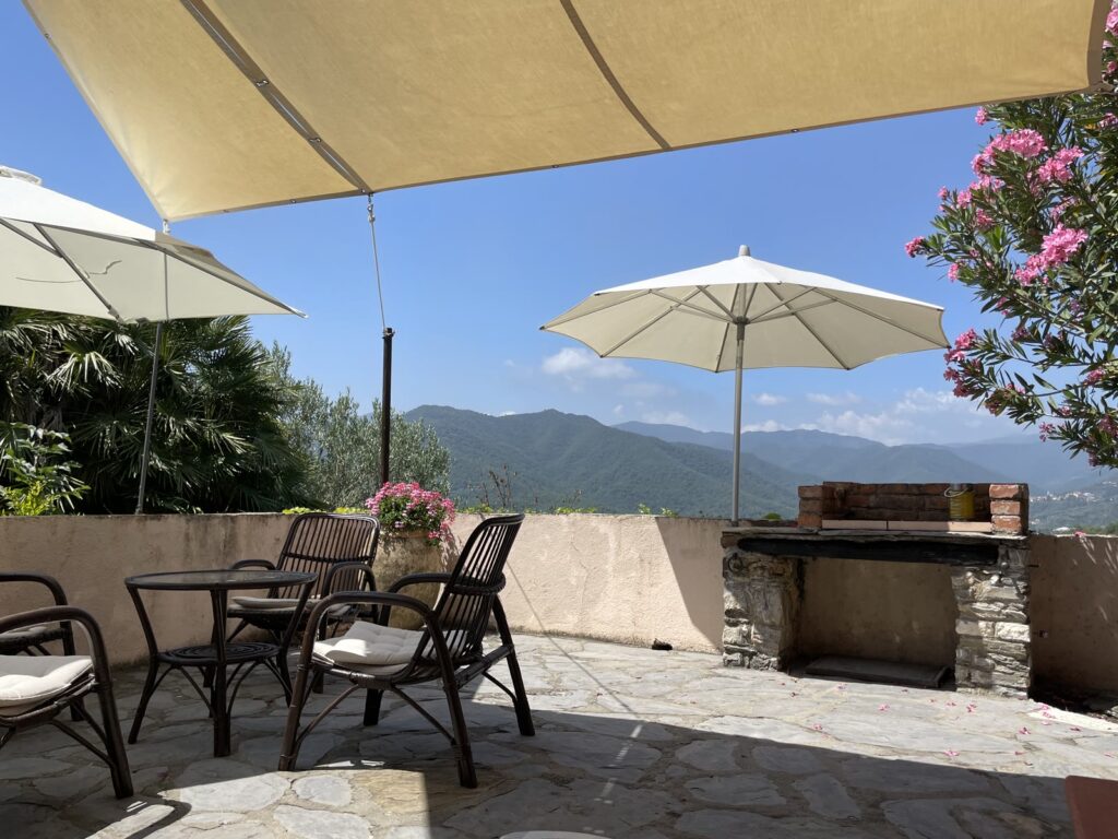 Sonnige Terrasse mit Sonnenschirmen, Sitzplätzen und Grill